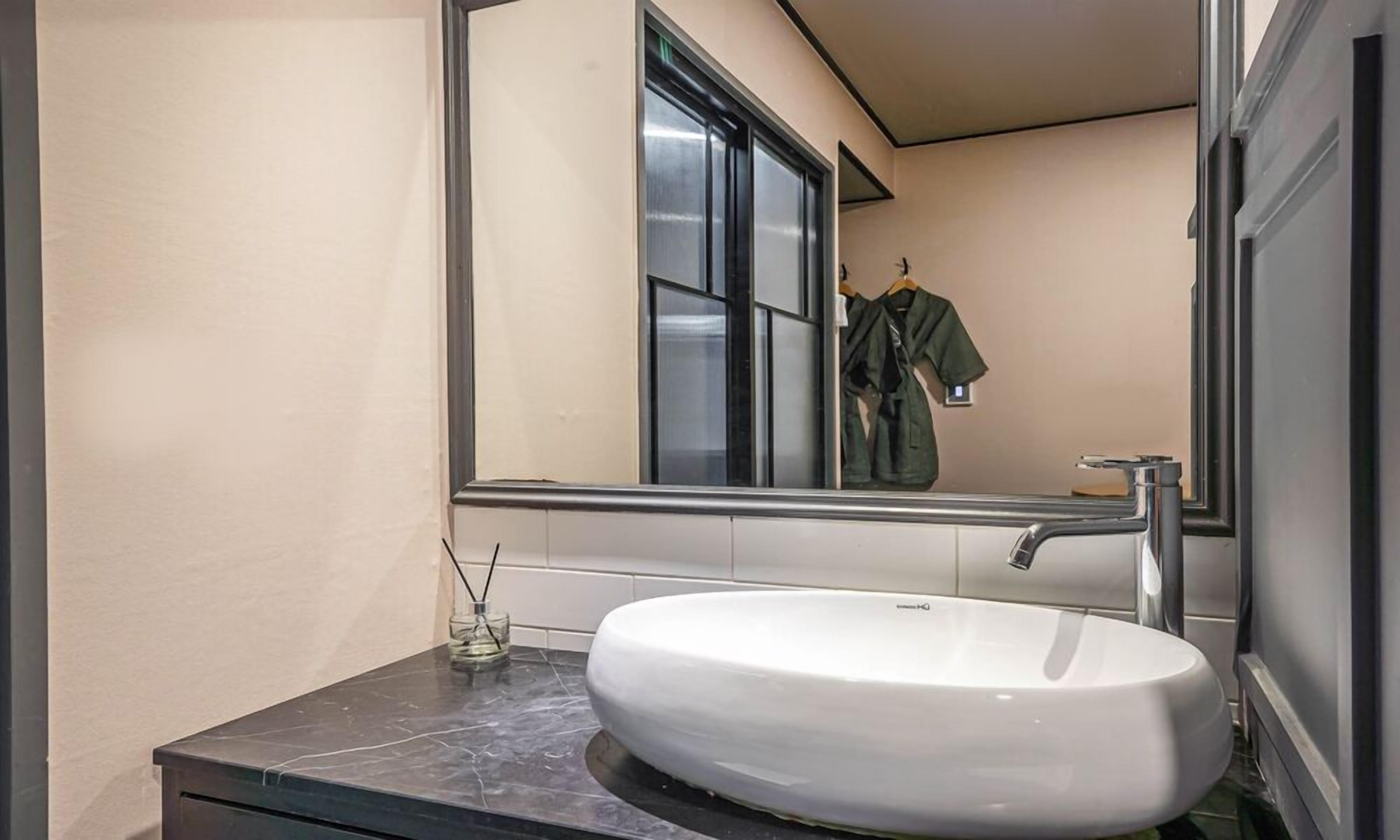 Un baño con un lavabo blanco, un espejo y una ventana.