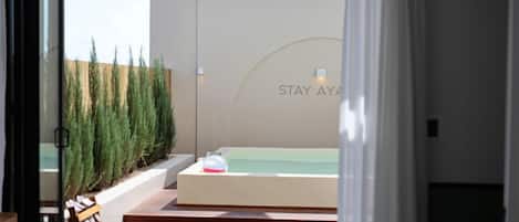Un espace spa moderne doté d’une grande baignoire, d’un banc en bois et d’un mur sur lequel est inscrit le texte « STAY AYA ».