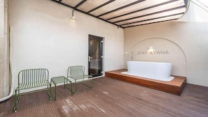 A spa area with a bathtub, two green chairs, and a wooden deck. - HOTEL STAY AYANA DAEJEON (Daejeon)