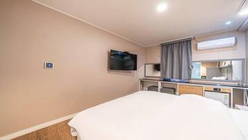 Habitación de hotel con cama, televisión montada en la pared, escritorio con espejo y aire acondicionado.