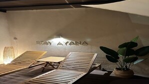 A room with a wall-mounted sign reading "STAY AYANA," wooden lounge chairs, a potted plant, and a lamp. - HOTEL STAY AYANA DAEJEON (Daejeon)