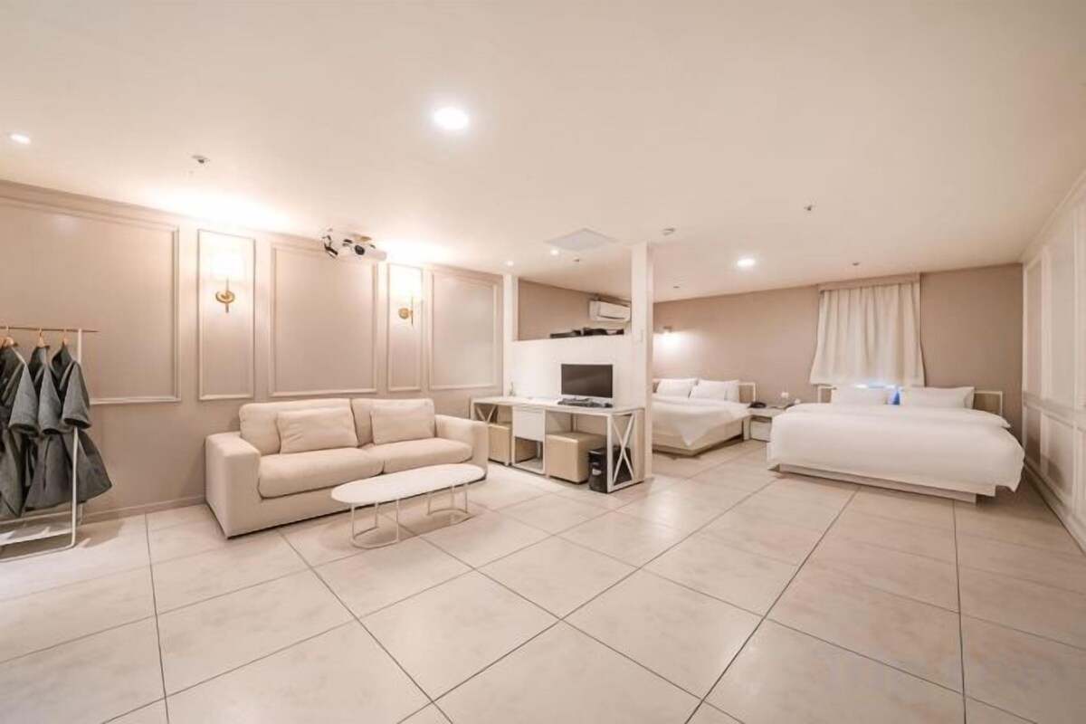 A hotel room with a bed, a sofa, a desk, and a TV.