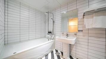 Un baño moderno con bañera, lavamanos y ducha. Las paredes están cubiertas de azulejos, y hay un espejo sobre el lavamanos.