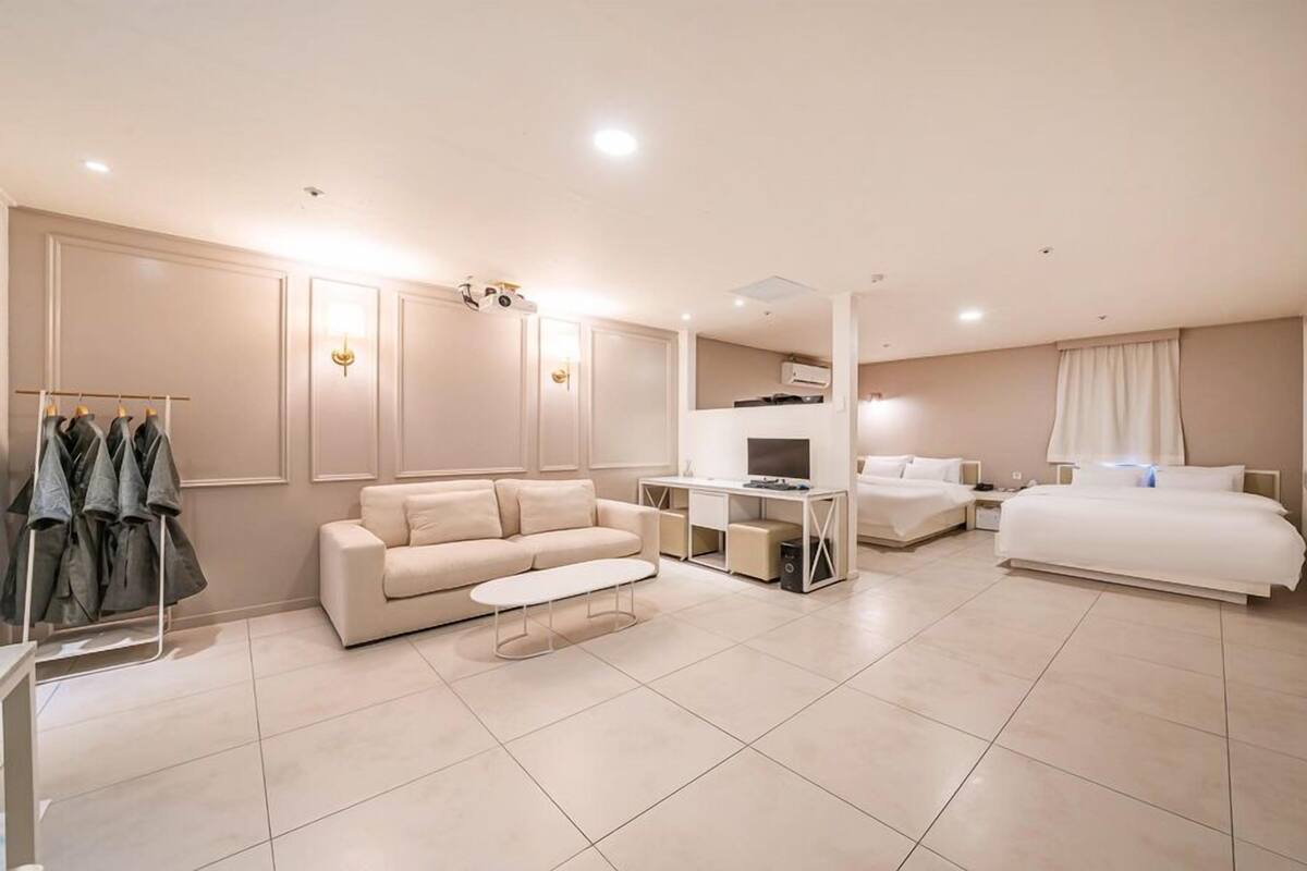 Una habitación de hotel moderna con sofá, cama, escritorio y televisor.