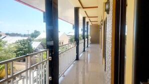A corridor with a tiled floor, black marble columns, and a railing. - Sasando Residence Kupang (Kupang)