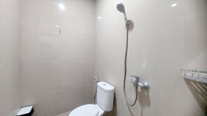 Shower area features a wall-mounted showerhead and handheld shower attachment.