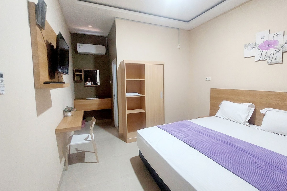 A hotel room with a bed, a desk, a chair, a wardrobe, and a bathroom.