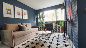 A living room with a sofa, coffee table, and potted plants. - Moderno e Vibrante na Augusta (São Paulo)