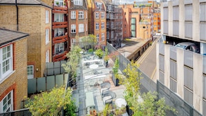 A multi-story residential building with a rooftop garden featuring outdoor furniture and potted plants. - No. 30 Knightsbridge (London)