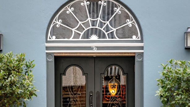 A double door with a decorative arch above, flanked by potted plants. - No. 30 Knightsbridge (London)