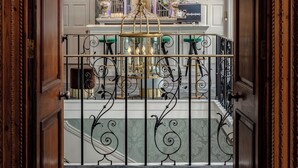 An ornate hotel lobby with a grand chandelier, a reception desk, and a decorative railing. - No. 30 Knightsbridge (London)