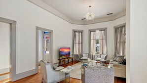 A spacious living room with a large TV, comfortable seating, and a chandelier. - Barclay Klum House by WanderLodges (Ashland)