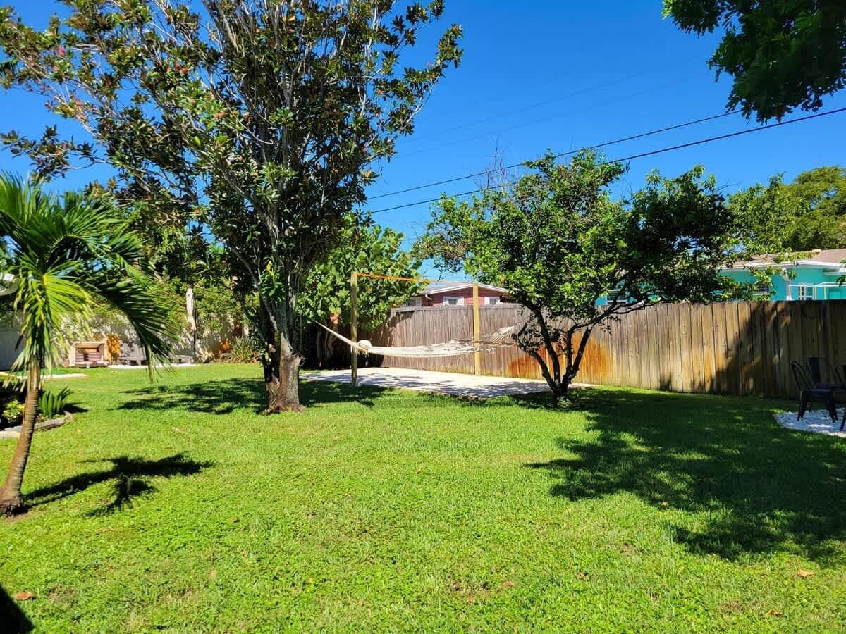 Ein Garten mit einer Hängematte, einem Holzzaun und einem Haus im Hintergrund.