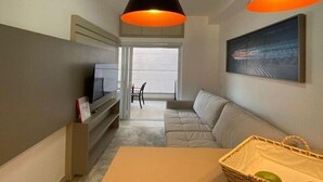 Un salon moderne avec un canapé, un téléviseur et un tableau accroché au mur.