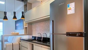 Une cuisine moderne dotée d’un réfrigérateur en acier inoxydable, d’un four encastré et d’un plan de travail noir.