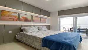 Une chambre moderne avec un grand lit, un luminaire au plafond et une vue sur le balcon extérieur.