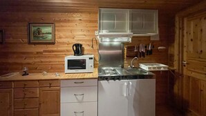 Cozinha compacta com micro-ondas, fogão, pia e armários de madeira.