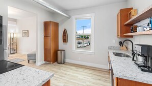 A modern kitchen with a large window, wooden cabinets, and a stainless steel sink. - The Night Owl Perch (Stanwood)