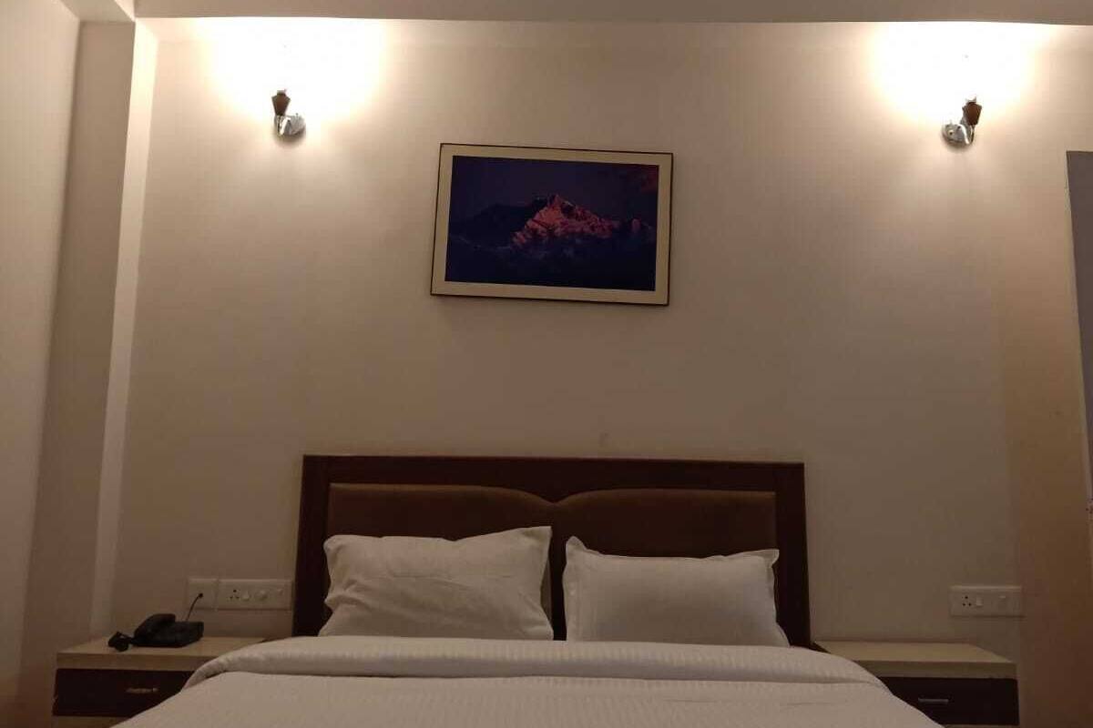 A hotel room with a bed, two bedside tables, a ceiling fan, and a wall-mounted picture.