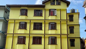 A multi-story yellow building with a sign reading "HOTEL ASTER" at the ground level. - Hotel Aster (Gangtok)