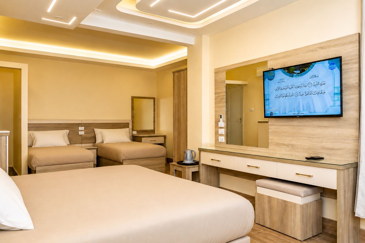 A hotel room with a large bed, a TV mounted on the wall, a bedside table, and a mirror.