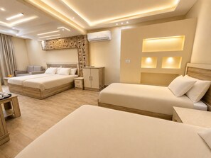 A hotel room with two beds, a wardrobe, a desk, and a wall-mounted air conditioner. - Hassan Pyramids Hotel (Giza)