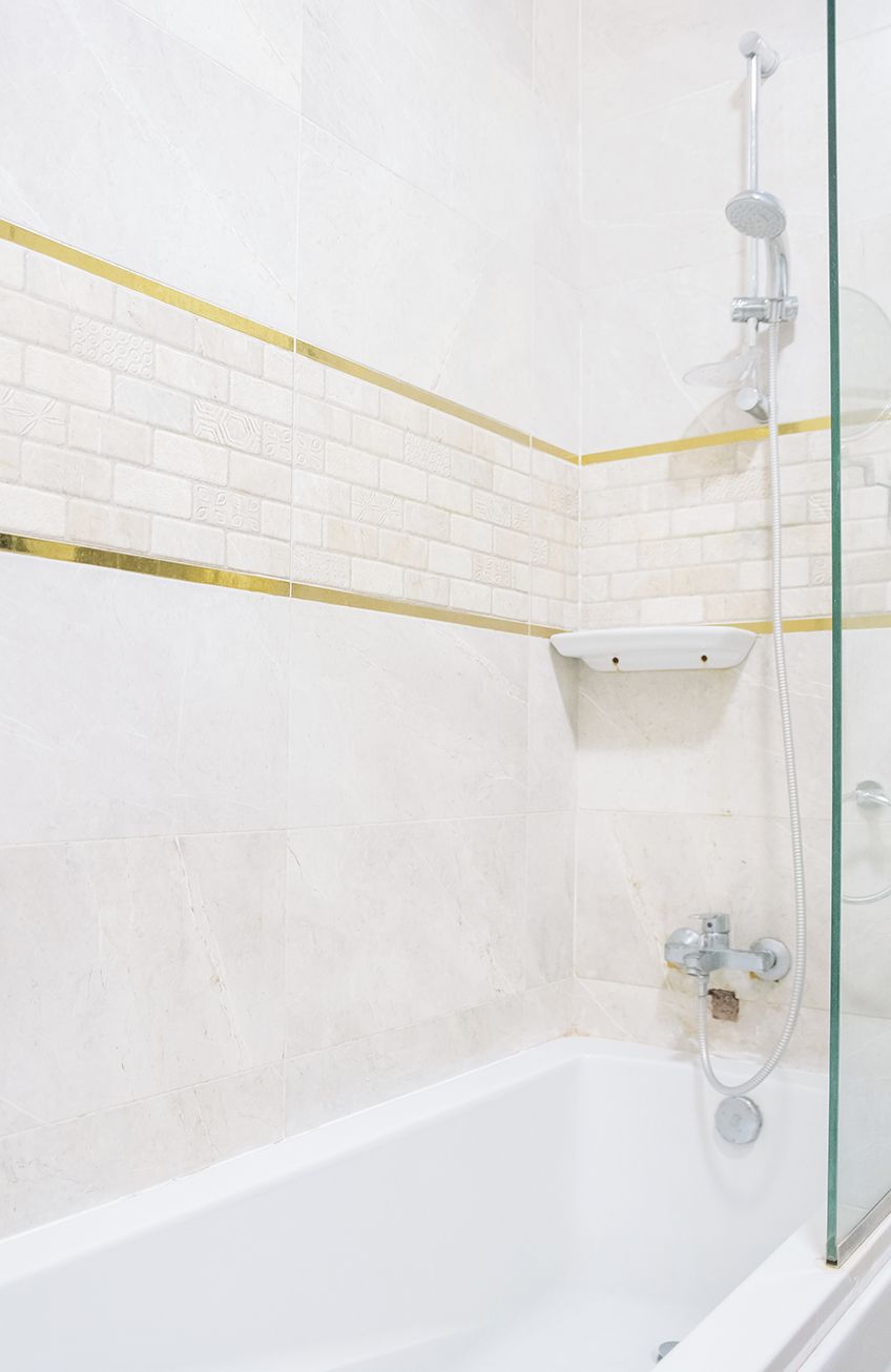 A modern bathroom with a white bathtub, a glass shower enclosure, and a yellow accent strip on the wall.