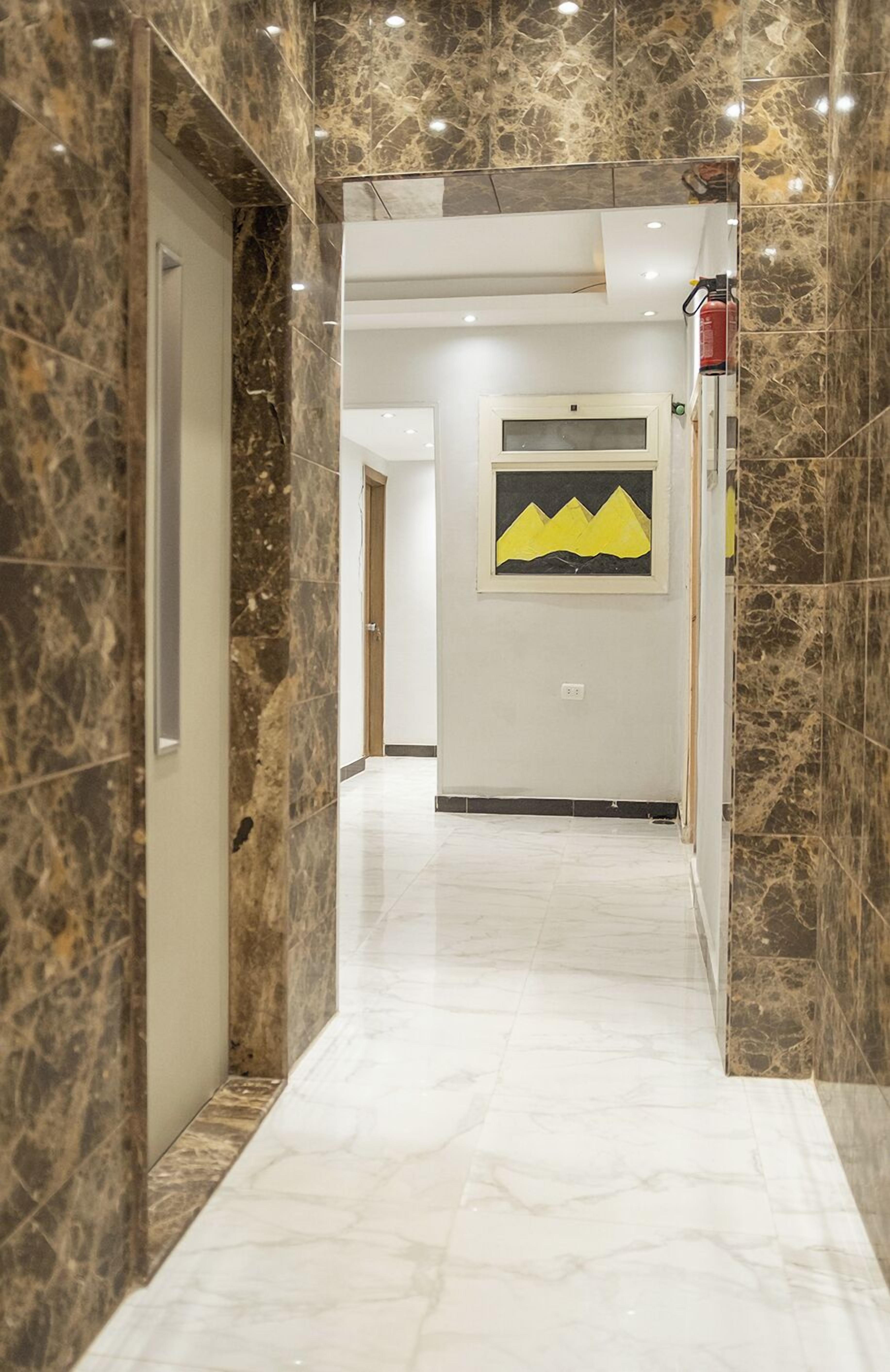 A hallway with marble walls and a framed artwork of yellow mountains.