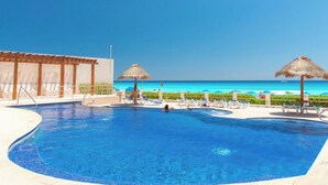 A clear blue pool with lounge chairs and umbrellas, a wooden pergola, and a view of the ocean. - Perfect vacation getaway Ocean ViewnWifi (Cancun)