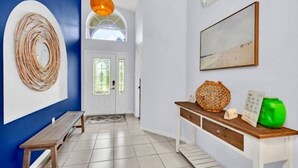 A hallway with a bench, a wooden console table, a woven wall decoration, and a framed picture on the wall. - NEW*4 Bdrm, 3 Bath* Updated Detached Pool Home, 10 Minutes to Disney (Kissimmee)