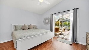 A bedroom with a bed, a ceiling fan, and a view of an outdoor patio. - NEW*4 Bdrm, 3 Bath* Updated Detached Pool Home, 10 Minutes to Disney (Kissimmee)