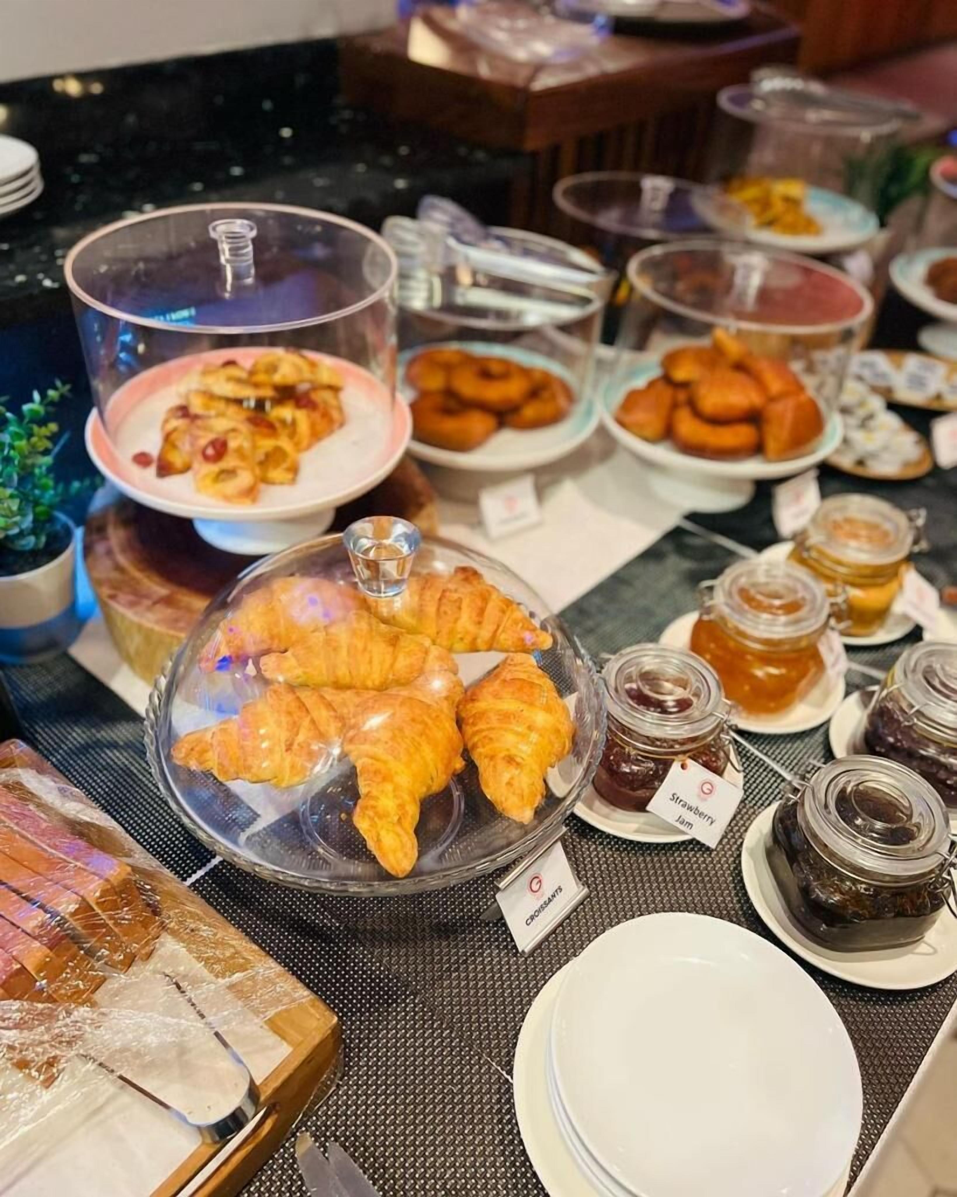 A buffet with various food items including croissants, pastries, and jams.