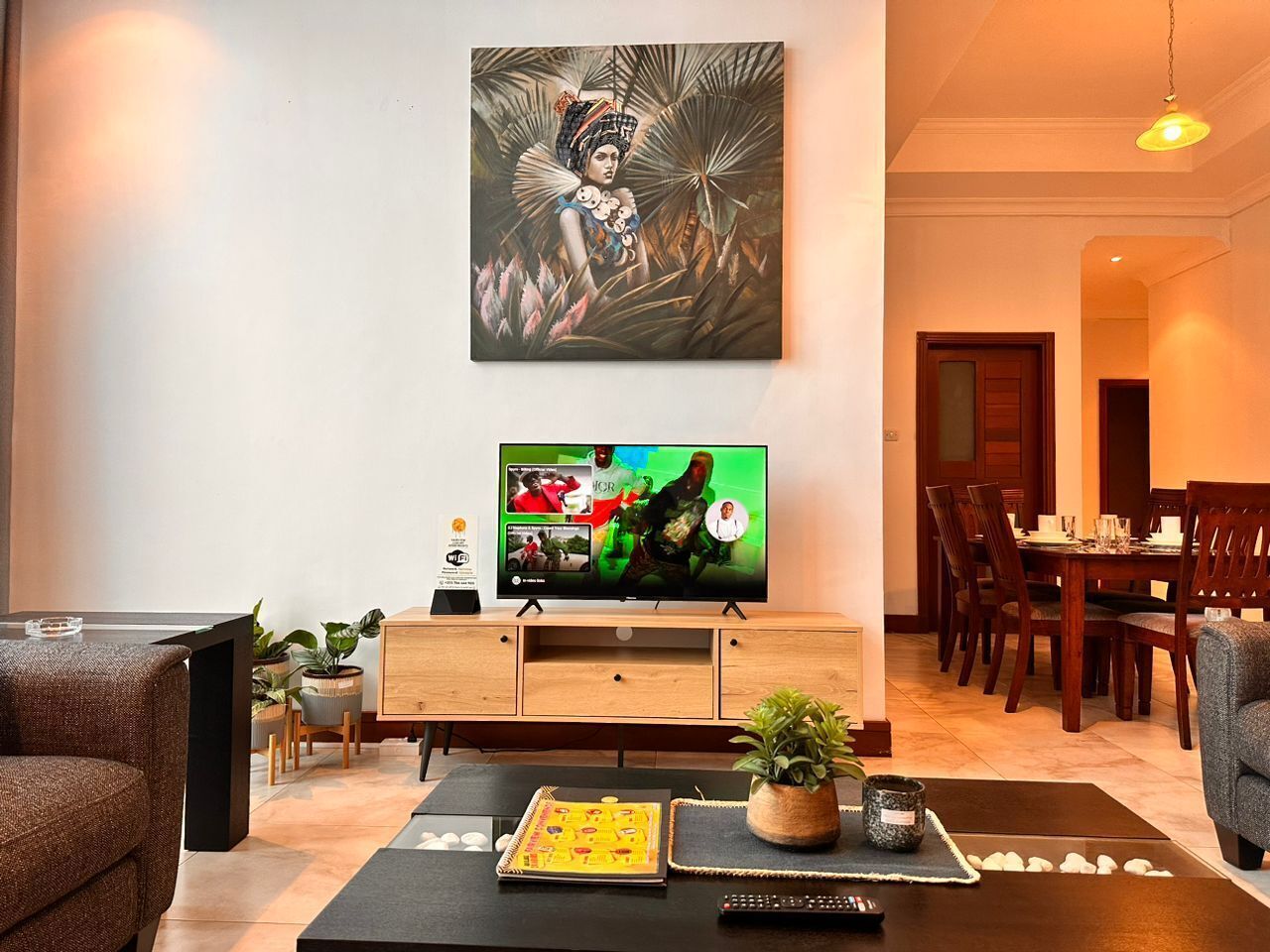 Una sala de estar moderna con un televisor de pantalla plana, un mueble de madera y un comedor con sillas y una mesa.