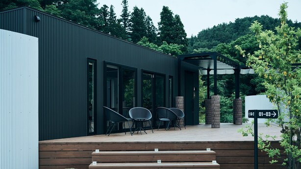 A modern building with a wooden deck, outdoor seating, and a brick fireplace. - BLANC FUJI (Fujiyoshida)