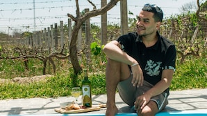 A man sitting on the edge of a blue swimming pool with a bottle and glasses on the side. - Glamping Toneles y Viñedos (San Juan Bautista)