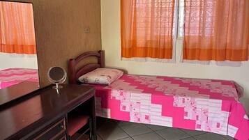 A bedroom with a bed, a desk, and a mirror.