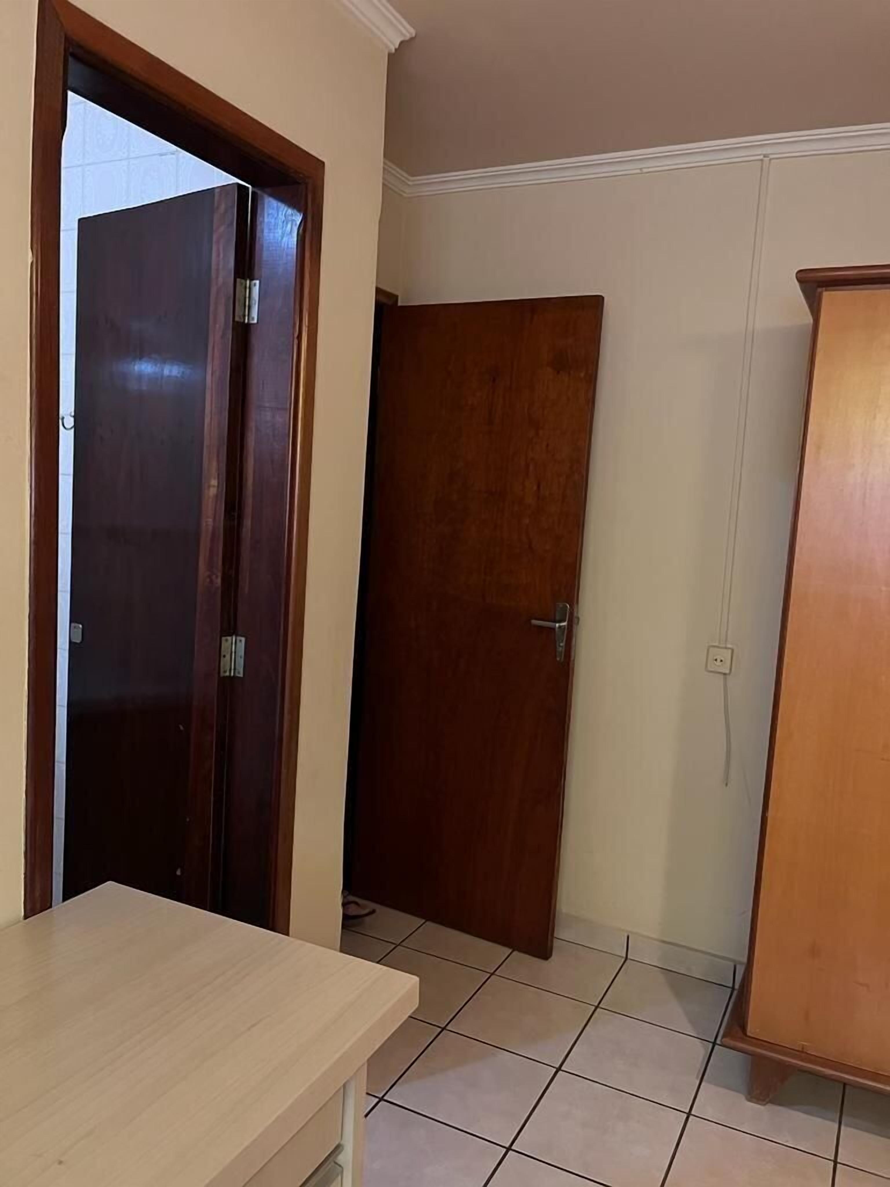 Een kamer met een houten deur, een tafeltje en een kast.