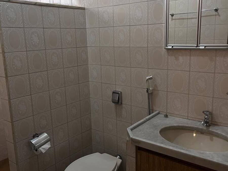 Baño con baldosas estampadas, inodoro, lavabo y espejo.