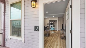 A modern interior with a wooden floor, a dining area, and a kitchen visible through an open door. - The Nightingale Nest (Stanwood)