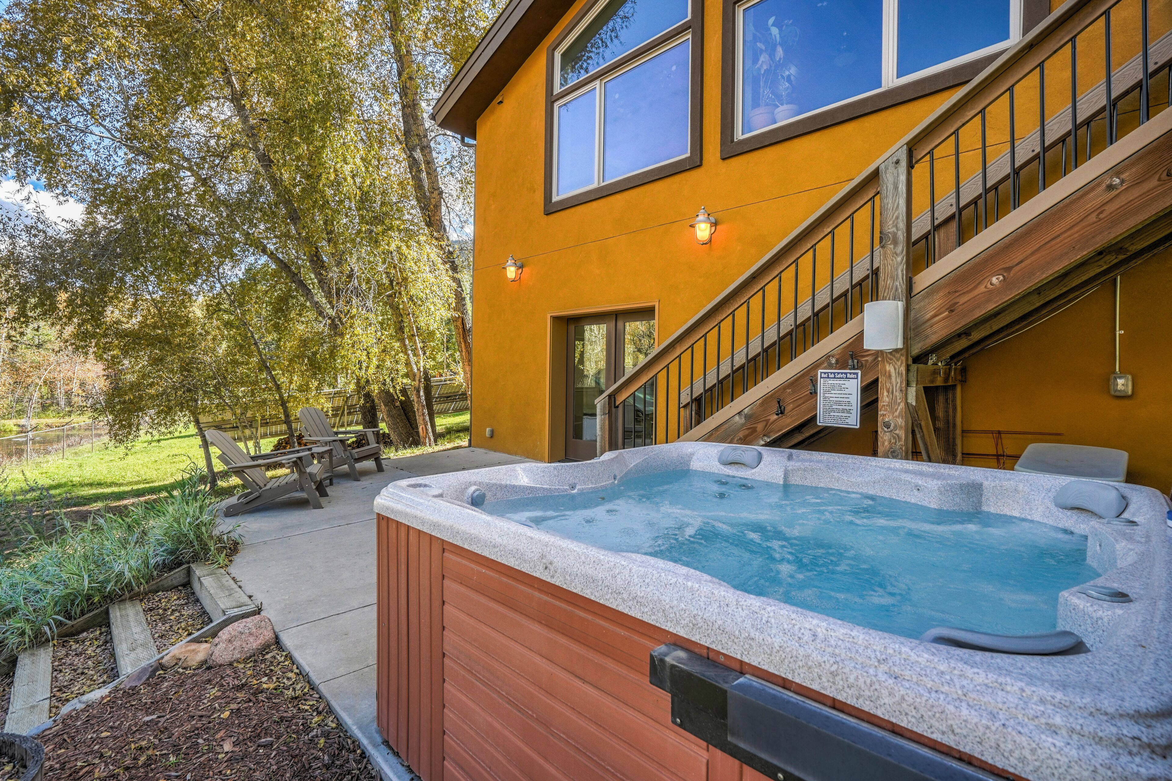 A hot tub in front of a yellow building with a staircase and outdoor seating.
