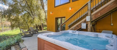 A hot tub in front of a yellow building with a staircase and outdoor seating.