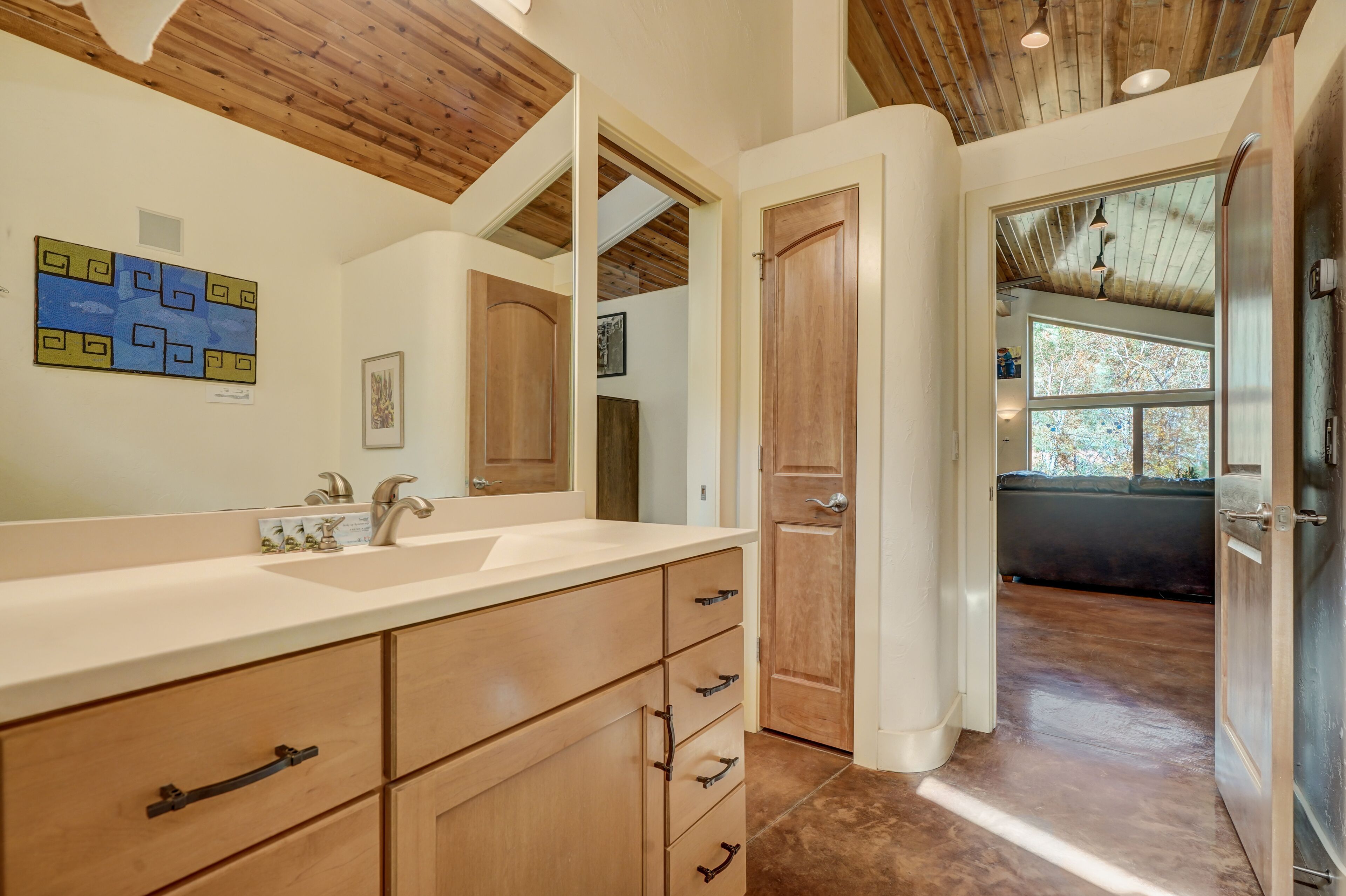 A bathroom with wooden cabinets, a large mirror, and a sink.