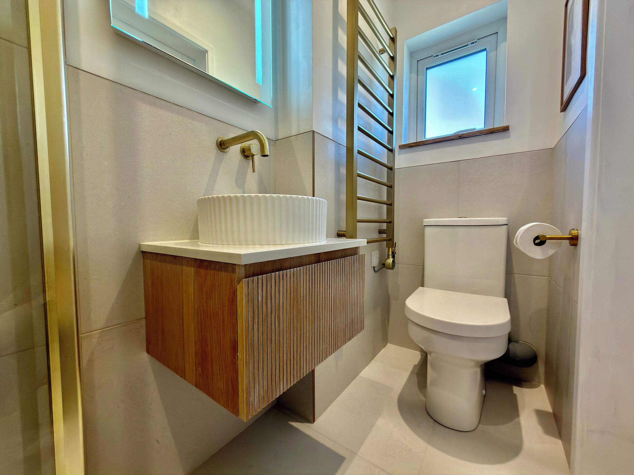 A bathroom with a white sink, a toilet, and a window with a view.