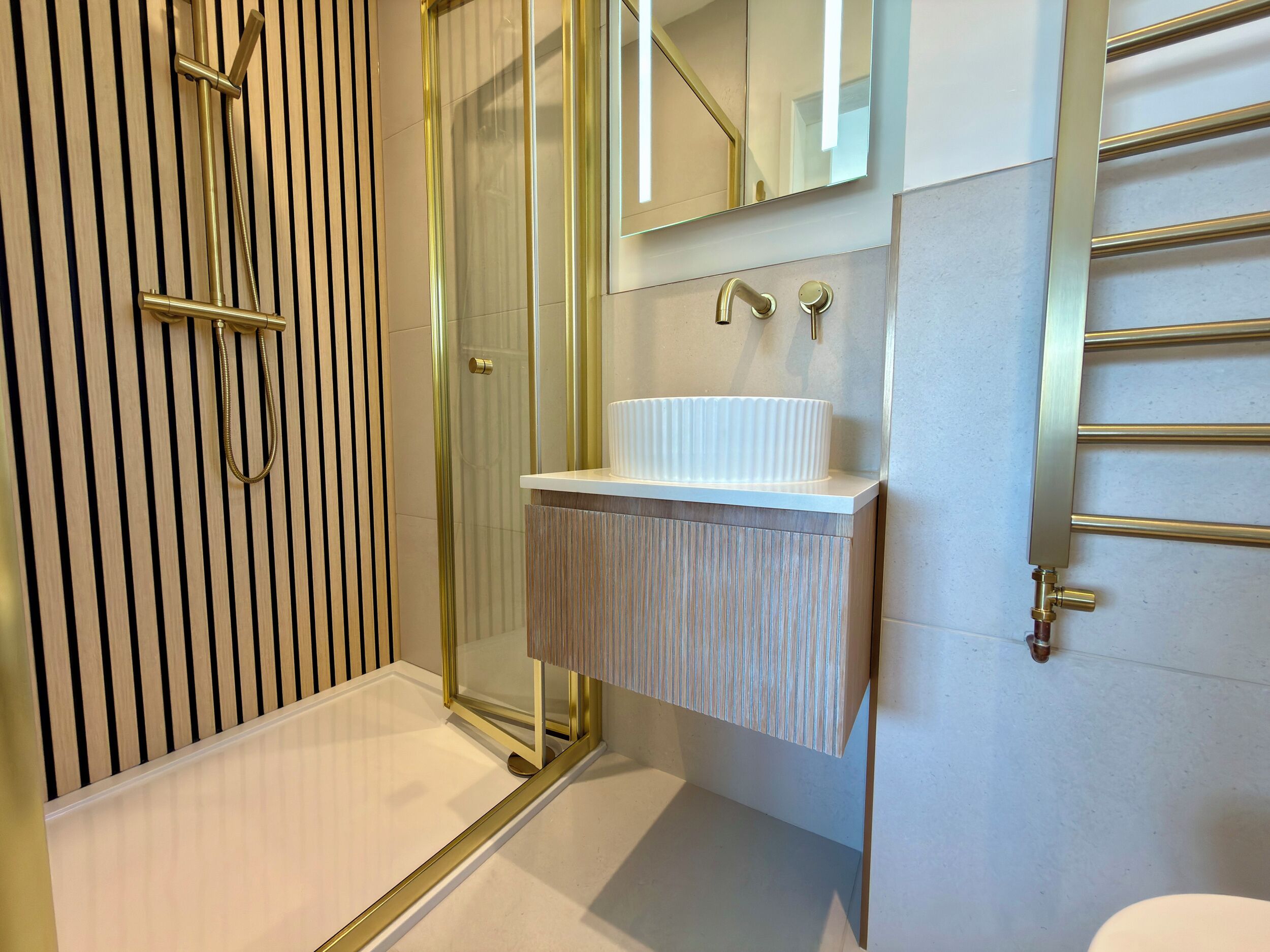 Ein modernes Badezimmer mit Duschkabine aus Glas, einem weißen Waschbecken mit Holzunterschrank und einem Spiegel darüber.