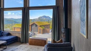 Una sala de estar moderna con ventanas amplias, un sofá, una mesa de centro y una chimenea.
