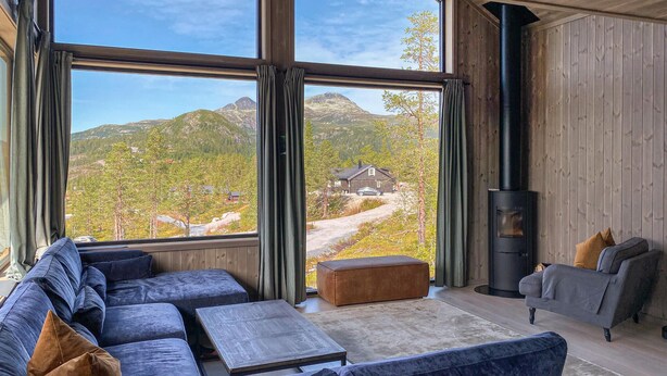Una sala de estar moderna con un ventanal grande, un sofá, una mesa de centro y una chimenea.