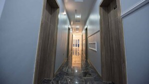 A hallway with wooden doors, marble flooring, and recessed lighting. - Imperial Boni Hotels and Resorts (Akure)