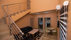 A compact living space with a staircase, a sofa, a small table, and a dining area. - Imperial Boni Hotels and Resorts (Akure)