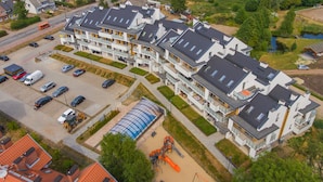 Een modern appartementencomplex met meerdere balkons, een parkeerplaats en een speeltuin.