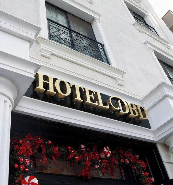Placa de hotel com o nome 'HOTEL CLUB' em letras douradas sobre fundo branco.